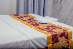 a bed with a brown and gold blanket on it at Skyline Guest House in Kinshasa