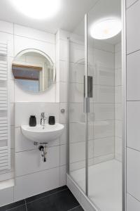 a white bathroom with a sink and a shower at Boardinghaus Perani in Augsburg +42 photos