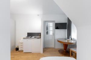 a white kitchen with a sink and a table at Boardinghaus Perani in Augsburg