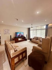 a living room with couches and a flat screen tv at LUXIRIOUS Homes in Dar es Salaam