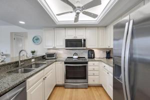 a kitchen with white cabinets and a ceiling fan at Compass Point 221 in Sanibel