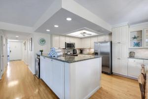 a kitchen with white cabinets and a refrigerator at Compass Point 221 in Sanibel