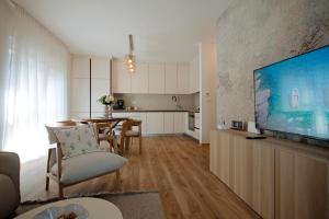 a living room with a large television and a kitchen at Apartman Lami in Krapina