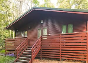 a small cabin with a wooden porch and stairs to it at Hideaway Lodges in Boʼness