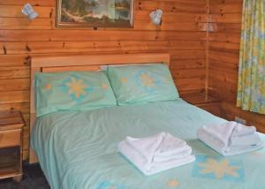 a bedroom with a bed with towels on it at Hideaway Lodges in Boʼness +3 photos