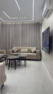 a living room with a couch and tables and a tv at شقة سحاب ابها in Abha