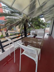 a table and chairs on a balcony with a palm tree at AmeriLanka Transit Hotel in Seeduwa