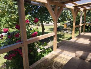 a wooden pergola with pink flowers in a yard at Wiesenrand in Neukalen
