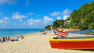 a beach with boats on the sand and people on the beach at Los Flamboyanes Cozy Suite in Aguadilla