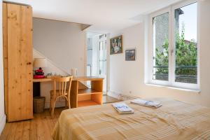 a bedroom with a bed and a desk and a window at La Cerisaie in Lyon