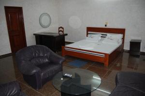 a room with a bed and a chair and a table at Link Hotel in Lokossa