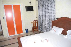 a bedroom with a bed and a chair and a television at Link Hotel in Lokossa