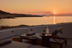 a sunset over the water with a table and chairs at Ostraco Houses in Pachaina