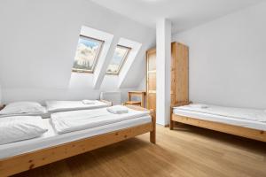 two beds in a room with white walls and wooden floors at Lenhart's Ryžovna by Mountain ways in Boží Dar