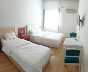 a hotel room with two beds and a desk and a window at Yaşar otel in Mersin