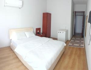 a bedroom with a large white bed and a wooden floor at Yaşar otel in Mersin