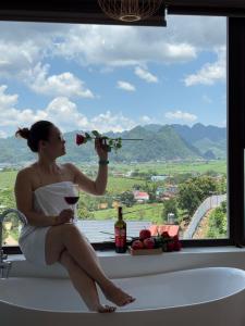 a woman sitting in a bath tub holding a flower at Lơ Mơ House in Làng Môn