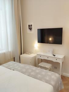 a white bedroom with a bed and a tv on the wall at Serenity Boutique Budapest in Budapest