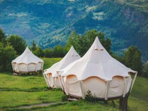three white tents in a field with mountains in the background at Glamping Tago in Khulo