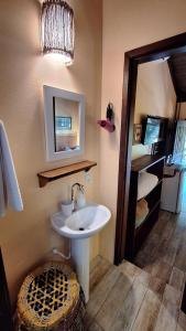 a bathroom with a sink and a mirror at Pousada Rosa & Canela in Praia do Rosa