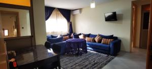 ein Wohnzimmer mit einem blauen Sofa und einem Tisch in der Unterkunft hôtel Benkachour in Oujda