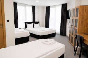 a room with two beds and a table and chairs at New Green Airport Hotel & Restaurant in Arnavutköy