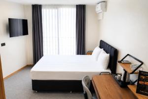 a bedroom with a bed and a table and a window at New Green Airport Hotel & Restaurant in Arnavutköy