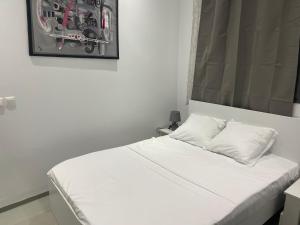a bed with white sheets and a picture on the wall at Rubis2 appart C2 in Ngaparou