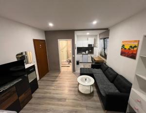 a living room with a black couch and a kitchen at Unterkunft Gjino Wirges in Wirges