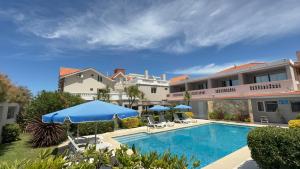 a swimming pool with umbrellas in front of a building at Ivamar Hotel & Apart in Ostende