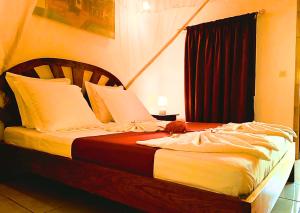 a bedroom with a large bed with white pillows at Fleurs d'Ylang in Nosy Be