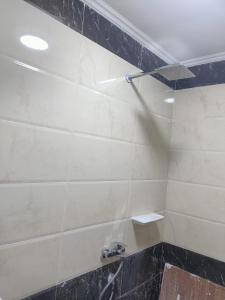 a bathroom with a shower with black and white tile at Your sweet house in Minshāt Şabrī