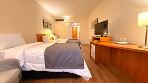 a hotel room with two beds and a desk with a television at Hotel & Residence Alphaville in Barueri