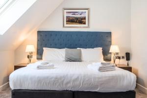 a bedroom with a large bed with a blue headboard at Cotswolds Apartment 3 Sleeps 9 in Chipping Norton
