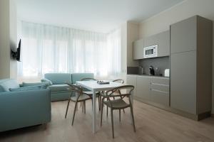 a living room with a table and chairs and a kitchen at Residence La Scogliera in Alassio