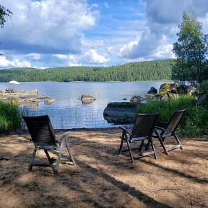 three chairs sitting on the shore of a lake at Suvela in Muurame