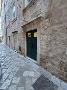 a stone building with a green door on a street at Lausa Dubrovnik Rooms in Dubrovnik
