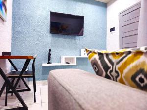 a living room with a couch and a tv on a wall at Domaine Béthania in Tadiénou