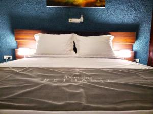 a bed with white pillows and two lights on it at Domaine Béthania in Tadiénou