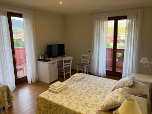 a bedroom with a bed and a desk with a television at Le Pavoncelle in Bosa