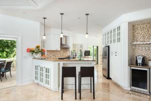 a kitchen with white cabinets and a island with bar stools at Villa with Sea View in Providenciales