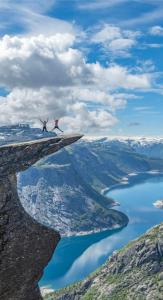 two people standing on a cliff over a body of water at Sentral leilighet Odda Trolltunga in Odda