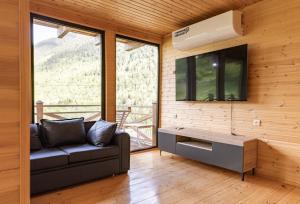 a living room with a couch and a flat screen tv at Cozy Cottages in Mestia