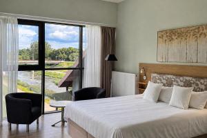 a hotel room with a bed and a large window at Viešbutis Banga in Tauragė