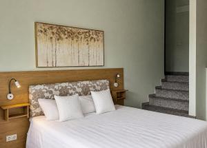 a bedroom with a bed with white sheets and stairs at Viešbutis Banga in Tauragė