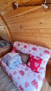 a bed in a wooden room with pillows on it at La Cabane douillette in Aups