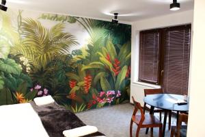 a living room with a painting of plants on the wall at Lyck Aparthotel in Ełk