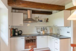 a kitchen with white cabinets and a stove top oven at Ferienwohnung Blücherkate II - Boldevitzer Rügenkaten in Parchtitz