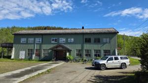 a white suv parked in front of a green building at Skorovas Fjellstue in Namsskogan