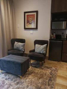 a living room with two chairs and a ottoman at Martin Villa in Somerset West +13 photos